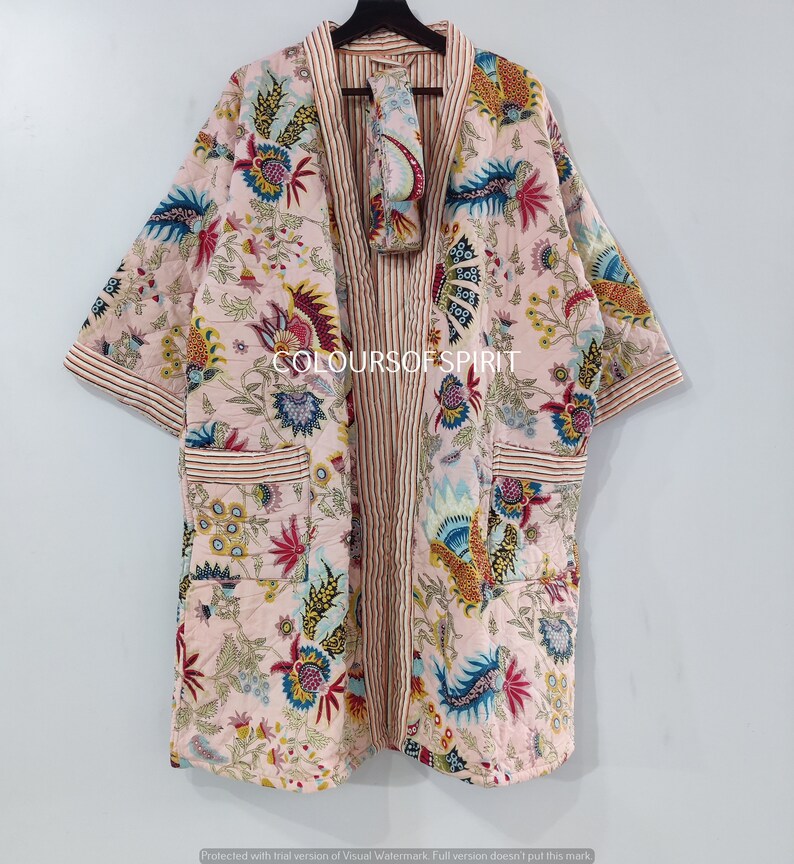 K&ouml;nnte beinhalten: Eine rosa-wei&szlig;e Baumwollrobe mit Blumenmuster und rot-wei&szlig;em Streifenbesatz. Die Robe hat eine passende Augenmaske.