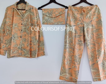 Op de afbeelding: Een perzikkleurige pyjamaset met een bloemenprint. De set bestaat uit een shirt met lange mouwen en een knoopsluiting en een bijpassende broek.
