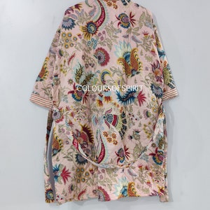 K&ouml;nnte beinhalten: Eine rosa-wei&szlig;e Robe mit floralem Muster, langen &Auml;rmeln und einem Bindeg&uuml;rtel. Die Robe hat ein farbenfrohes Paisley-Muster in den Farben Blau, Rot, Gelb und Gr&uuml;n. Der Text "COLOURSOFSPIRIT" ist auf die Robe gedruckt.
