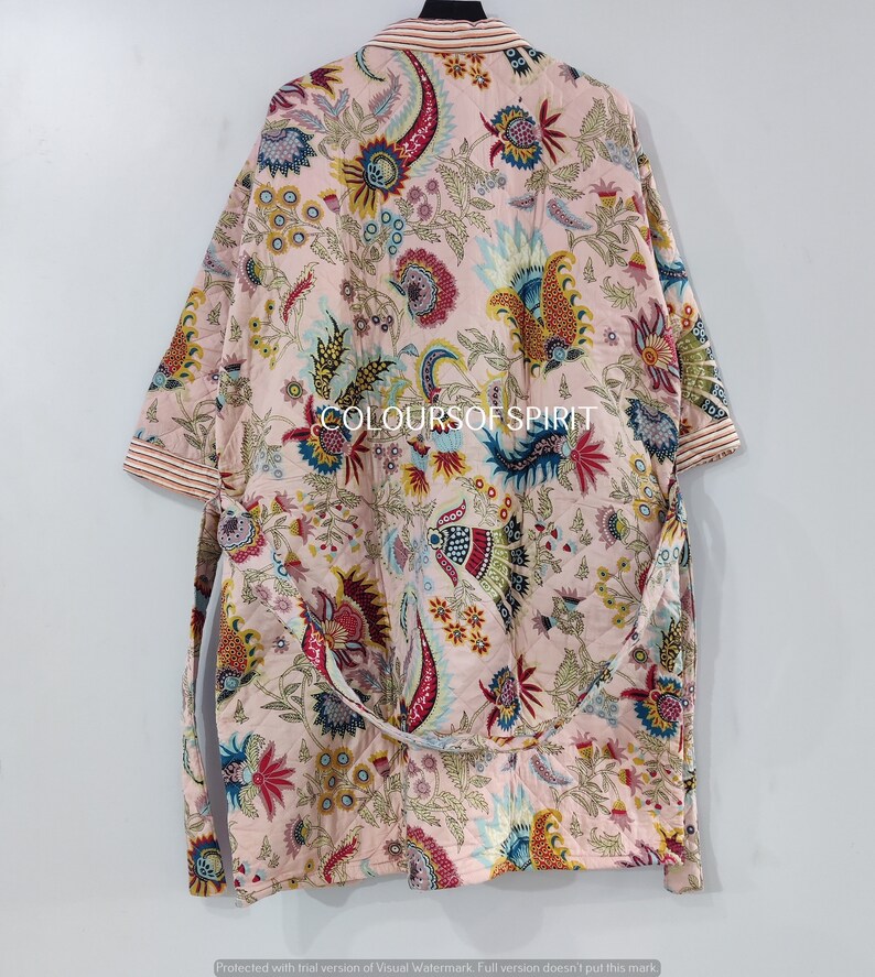 K&ouml;nnte beinhalten: Eine rosa-wei&szlig;e Robe mit floralem Muster, langen &Auml;rmeln und einem Bindeg&uuml;rtel. Die Robe hat ein farbenfrohes Paisley-Muster in den Farben Blau, Rot, Gelb und Gr&uuml;n. Der Text "COLOURSOFSPIRIT" ist auf die Robe gedruckt.