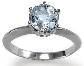 May include: A silver ring with a light blue aquamarine gemstone set in a prong setting.