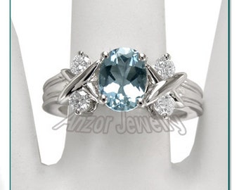 May include: A silver ring featuring an oval, light blue gemstone as the centerpiece, flanked by smaller, clear gemstones. The ring has a decorative design with the text "Anzor Jewelry" and "Style Number: R664".