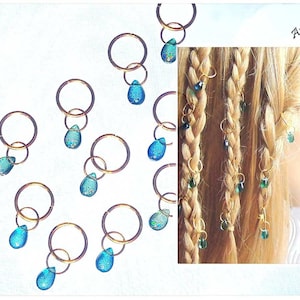 May include: Ten gold hair rings with teardrop-shaped blue glass beads. The rings are shown on a white background and on a model's blonde hair.