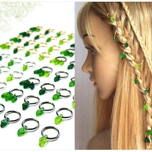 以下が含まれることがあります： 髪を編むための緑の葉の形をしたヘアリングのセット。リングは金属製で、小さな緑の葉のチャームが付いています。リングはクローズアップ画像と、編まれた髪につけられた状態で見ることができます。