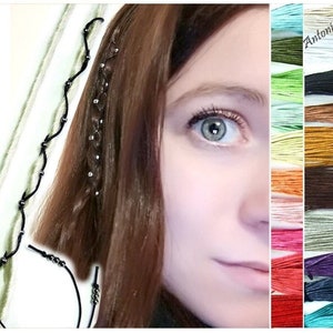 May include: A close-up of a woman's eye with a braid in her hair. The braid is decorated with small silver beads. A black cord with silver beads is shown in the image. The image also shows a variety of colors of cord, including blue, green, red, orange, yellow, brown, and black.