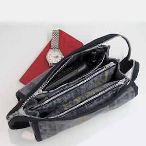TROUSSE multi usage avec trois compartiments fermés par des fermetures éclair métalliques, ornée de motifs d’inspiration asiatique dorée.