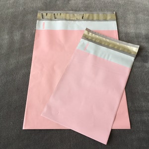 May include: Two pink mailing envelopes with white and gold trim. The envelopes are made of a lightweight, durable material and are perfect for shipping small items.