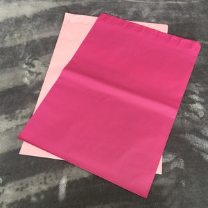 Puede incluir: Dos sobres de envío rosas, uno encima del otro. El sobre de arriba es de un tono rosa más oscuro.