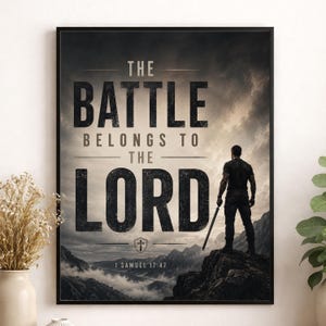 以下が含まれることがあります： THE BATTLE BELONGS TO THE LORDおよび1 SAMUEL 17:47というテキストが記された額装済みのウォールアートプリント。剣を持ち、曇り空の下で山岳風景を見下ろす岩場の崖の上に立つ人物が描かれています。