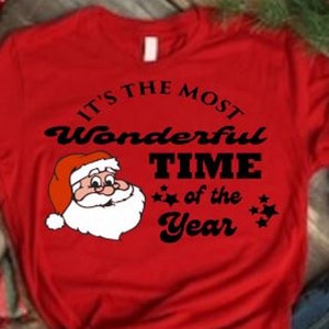 Pode incluir: Camiseta vermelha com um gráfico preto do Papai Noel e o texto "It's the most Wonderful Time of the Year".