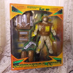 May include: A Commando Extreme action figure playset with a brown and tan soldier figure holding a gun. The set includes a backpack, a gun, and other accessories. The packaging is yellow, green, and red with the words "Commando Extreme" printed on it.