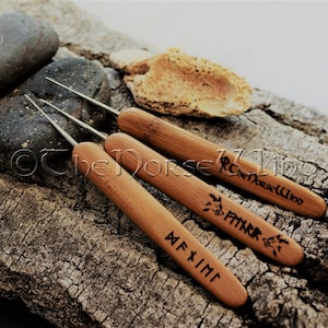 Könnte beinhalten: Drei Häkelnadeln aus Holz mit Metallspitzen. Die Nadeln sind mit nordischen Runen und dem Text "The Norse Wind" graviert.