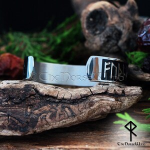 May include: A silver bracelet with a black inscription of the runes "F&THORN;R&Yacute;", which is the name of the Norse goddess Freyja.
