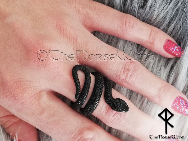 K&ouml;nnte beinhalten: Ein schwarzer Schlangenring mit strukturierter Oberfl&auml;che. Der Ring wird an einem Finger getragen und umschlie&szlig;t den Finger.