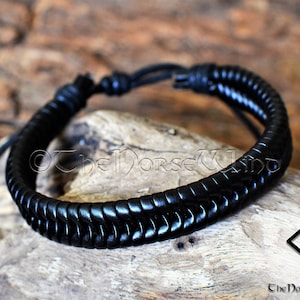 May include: Black leather bracelet with a braided design. The bracelet has a simple knot closure.