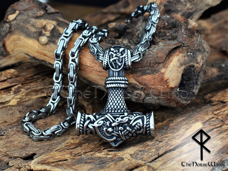 May include: A silver Mjolnir pendant necklace with intricate knotwork designs and a silver chain. The pendant is a replica of Thor's hammer, a symbol of strength and protection in Norse mythology.