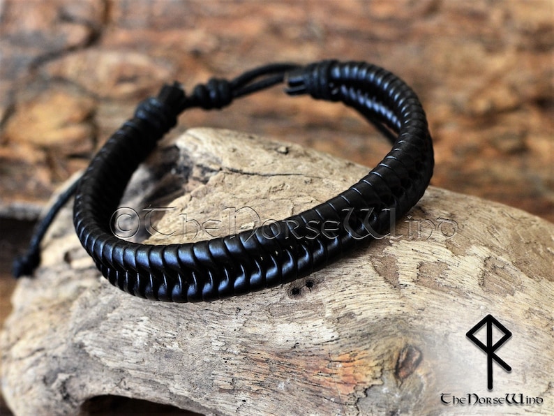 May include: Black leather bracelet with a braided design. The bracelet is tied with a knot on one end.