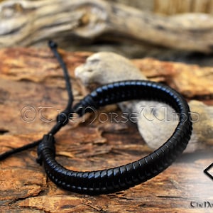 May include: Black leather bracelet with a braided design. The bracelet is adjustable with a sliding knot.