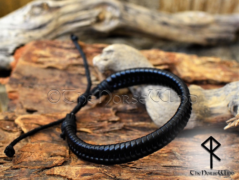 May include: Black leather bracelet with a braided design. The bracelet is adjustable with a sliding knot.