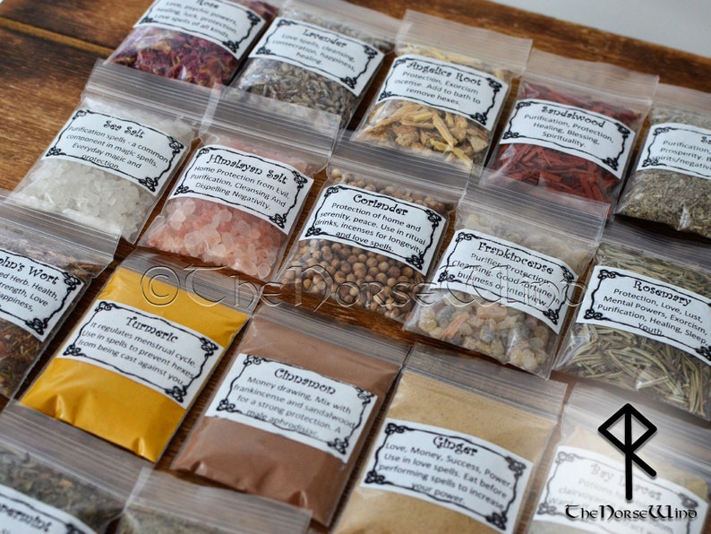 May include: A collection of small clear plastic bags filled with various herbs, spices, and salts. Each bag has a label with the name of the ingredient and its uses in magic and spell work. The labels are printed in black and white with a decorative border. The bags are arranged in rows on a wooden surface. The Norse Wind logo is visible in the bottom right corner.