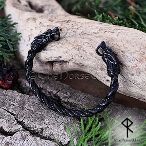 May include: Black braided metal bracelet with wolf head accents. The bracelet is open and has a twisted design.
