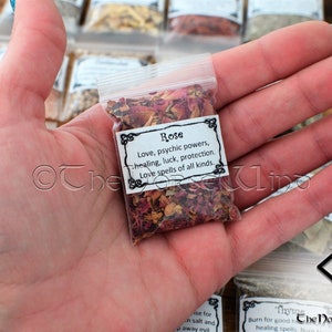 May include: A small clear plastic bag filled with dried rose petals. The bag has a white label with black text that reads "Rose Love, psychic powers, healing, luck, protection. Love spells of all kinds."
