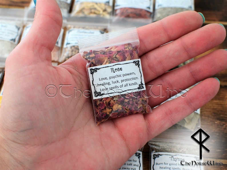 May include: A small clear plastic bag filled with dried rose petals. The bag has a white label with black text that reads "Rose Love, psychic powers, healing, luck, protection. Love spells of all kinds."