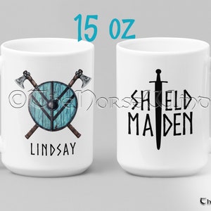 May include: White ceramic mug with a 15 oz capacity. One side features a shield with crossed axes and the name "LINDSAY". The other side features a sword and the text "SHIELD MAIDEN".