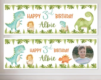 May include: Two birthday banners with a white background, featuring watercolor illustrations of dinosaurs and tropical leaves. The text reads "Happy 3rd Birthday Albie". One banner includes a photo of a young boy.