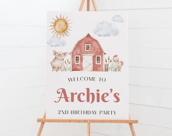 May include: Welcome to Archie's 2nd Birthday Party sign with a red barn, a pig, a chicken, clouds, and a sun. The sign is on a wooden easel.