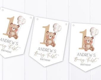 May include: Three white pennant banners with brown teddy bear illustrations and the text "Andrew's Beary First Birthday".