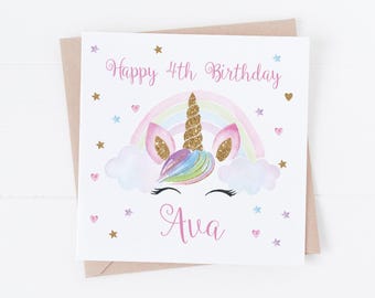 May include: A square greeting card featuring a unicorn illustration with a gold glitter horn, a pastel rainbow, and clouds. The text reads Happy 4th Birthday and the name Ava in pink script. Small gold, pink, and blue stars and hearts surround it.