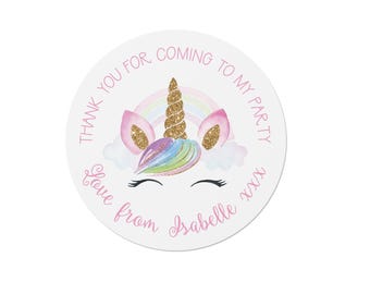 May include: A circular sticker featuring a unicorn illustration with a gold glitter horn, pink ears, and a pastel rainbow mane. The text reads THANK YOU FOR COMING TO MY PARTY and Love from Isabelle xxx in pink script and block lettering.