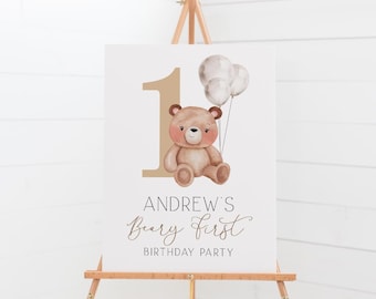 May include: A white sign with a brown teddy bear holding balloons. The sign says "Andrew's Beary First Birthday Party".