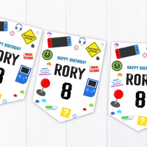 Könnte beinhalten: Drei weiße Bannerflaggen mit einem Gamer-Thema. Jede Flagge hat ein anderes Design mit einem Videospiel-Controller, einem Joystick und einer Spielekonsole. Die Flaggen sagen "Happy Birthday Rory 8".