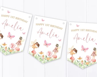 May include: Three white pennant flags featuring the text HAPPY 1ST BIRTHDAY Amelia in gold and pink script. The design includes watercolor illustrations of fairies standing on mushrooms, pink butterflies, and green foliage with colorful flowers.
