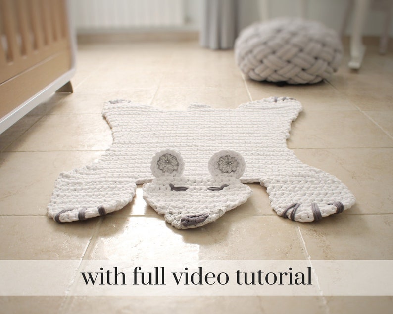 May include: White crocheted bear rug with grey ears and nose. The rug is on a light brown tiled floor. "with full video tutorial" is written in black text at the bottom of the image.
