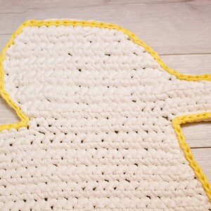 May include: White crocheted rug shaped like a duck with a yellow border.