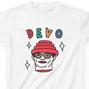 May include: White t-shirt with a cartoon illustration of a person wearing a red, multi-layered hat and glasses. The text "DEVO" is above the illustration in colorful letters.