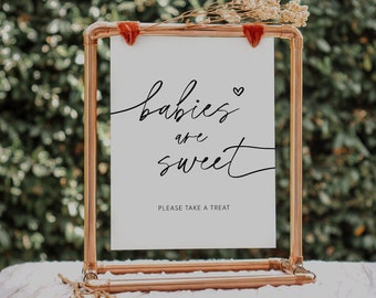 May include: A copper pipe sign holder with a white sign that says "babies are sweet" with a small heart symbol. The sign also says "Please take a treat".