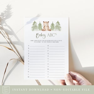 May include: A printable baby shower game card with a brown bear illustration and green trees. The game instructions read "Baby ABC's Name a baby related item that begins with each letter of the alphabet. The first person to finish wins!"