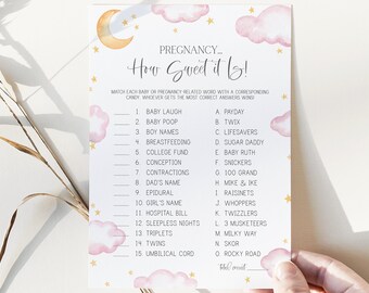 May include: A printable baby shower game with a pink and white cloud design. The game is called "How Sweet It Is!" and asks players to match pregnancy-related words with candy names.