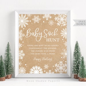 May include: Printable baby shower game sign with a brown background and white snowflakes. The sign says "Baby Sock Hunt" and includes instructions for the game. The text says "There are baby socks hidden throughout the shower. The person who finds the most wins a prize! Happy Hunting!"