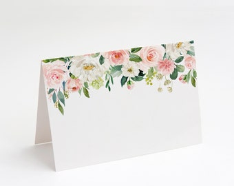 May include: A white place card with a floral border of pink and white roses, greenery, and white flowers. The floral border is at the top of the card.