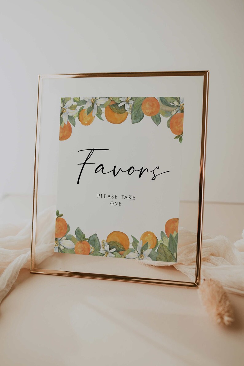 May include: A white sign with a gold frame and a floral border of orange blossoms and oranges. The sign says "Favors" and "Please Take One".