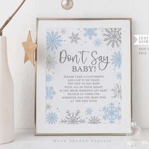 Puede incluir: Un cartel de juego imprimible "¡No digas bebé!" para un baby shower de invierno. El cartel presenta un diseño de copo de nieve azul y gris con las instrucciones del juego impresas en texto gris.