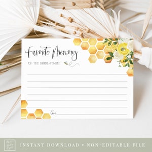May include: A white card with a honeycomb pattern and yellow flowers. The text "Favorite Memory of the Bride-to-Bee" is written in black cursive. There is a small bee illustration next to the text.