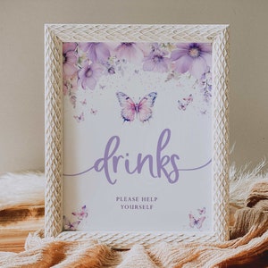 May include: A white framed sign with a purple butterfly and floral design. The sign says "drinks" and "please help yourself".