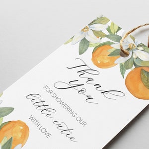May include: White thank you tag with orange blossoms and oranges. The text reads "Thank you for showering our little cutie with love."