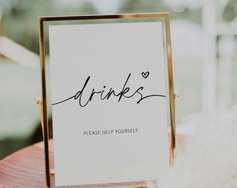 May include: A gold-framed sign with the word "drinks" written in cursive with a small heart symbol. The sign also says "Please help yourself".